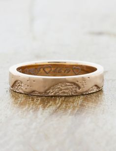 an engraved wedding ring with hearts on it