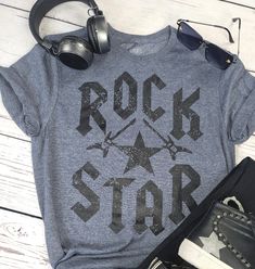 Color: Navy Blue Rock Star tee shirt is designed to stand out with bold rock style lettering and an eye-catching star in the center. This long-lasting, lightweight garment is made of high-quality, breathable cotton to ensure superior comfort and durability. UNISEX SIZING SIZE DOWN FOR FITTED, TRUE TO SIZE FOR A LOOSE FIT, AND SIZE UP FOR OVERSIZED! PLEASE TAKE YOUR BODY TYPE INTO CONSIDERSATION WHEN CHOOSING. SMALL: 2-6 MEDIUM: 6-8 LARGE: 8-12 XL: 12-14 2XL: 14-18 3XL: 18-22 Trendy Relaxed Fit T-shirt With Star Print, Rock And Roll Style T-shirt For Summer Streetwear, Summer Rock Style T-shirt For Streetwear, Rock Style Graphic Print T-shirt For Summer, Casual Slogan T-shirt For Concert, Rock Style T-shirt For Summer Concerts, Trendy Star Print Streetwear T-shirt, Casual Summer Tops With Star Logo, Graphic Tee With Star Logo For Summer