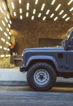 a blue jeep parked in front of a building with lights on it's side