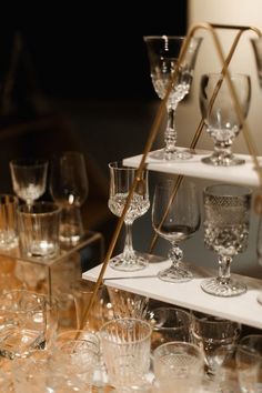 many wine glasses are lined up on a shelf with gold handles and glassware in the foreground