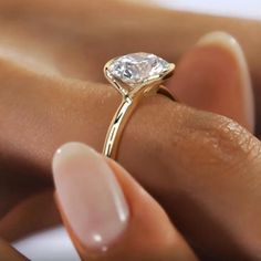 a woman's hand holding a ring with a white diamond on the middle finger