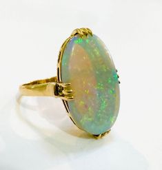 an opalite ring is sitting on a white surface with gold trimmings