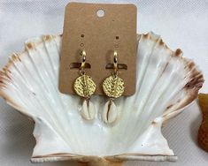 Elevate your beach style with these stunning Hammered Disc and Cowrie Shell Earrings. This beautiful pair is handcrafted with gold plated brass disc beads and natural cowrie shells, making them versatile enough to wear every day and suitable for any occasion. The lightweight design and easy to wear leverback hoops make them a comfortable choice for all-day wear. The earrings measure 5 cm in length, with the 24K gold plated hoops measuring 15 mm in diameter and 1.6 cm in length. These statement e Gold Small Hoop Jewelry For The Beach, Gold Hoop Jewelry For Beach, Gold Drop Earrings For Vacation, Bohemian Small Hoop Earrings For Beach, Summer Beach Hoop Earrings, Gold Jewelry For Summer Beach, Gold Coastal Jewelry For Vacation, Coastal Gold Jewelry For Vacation, Small Hoop Earrings For Summer Beach