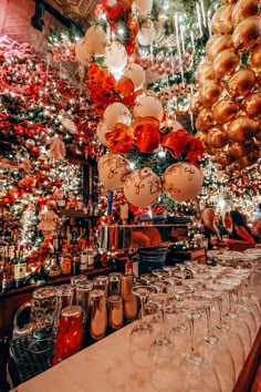 many wine glasses are lined up on the bar in front of christmas trees and lights