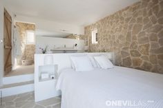 a bedroom with stone walls and white bedding