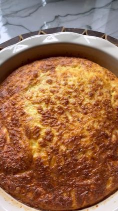 a round casserole sitting on top of a white plate next to a glass table