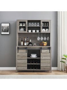 an open cabinet with wine glasses and bottles on the top, in front of a gray wall