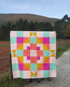 a person standing next to a colorful quilt