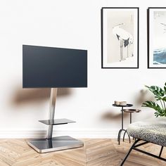 a television sitting on top of a metal stand in front of a wall mounted flat screen tv