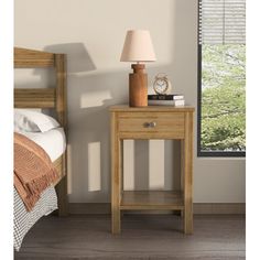 a nightstand with a clock on it next to a bed and window in a room