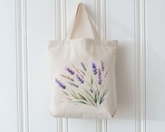 a tote bag hanging on a white door with lavender flowers painted on the front