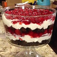 a layered dessert in a glass dish on a counter top with red and white toppings