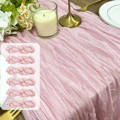 a pink table cloth with white flowers on it and candles in the middle next to them