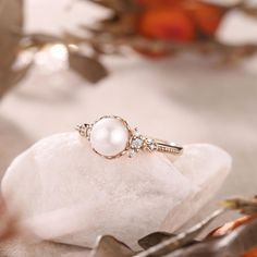 a pearl and diamond ring sitting on top of a piece of white rock next to some silverware