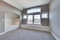 an empty room with gray walls and windows