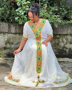 a woman wearing a white dress with colorful designs on it's waist and neck