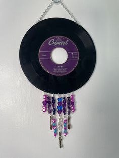 an old record hanging from a chain with beads and chains attached to the side of it