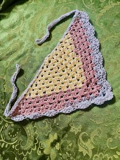 a crocheted triangle laying on top of a green blanket