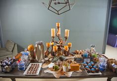 a table topped with lots of desserts and candles next to a chandelier