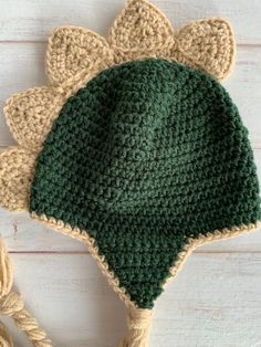 a crocheted green and beige hat sitting on top of a white wooden table