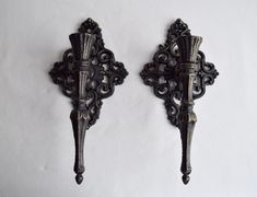 two ornate iron sconces on a white wall