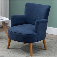 a blue chair sitting on top of a rug next to a table with a cup