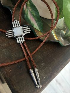 "This awesome bolo tie has a southwestern cross design and agate stone centerpiece.  Our bolos pair nicely with many of our belt buckles! They make wonderful gifts.    The western bolo tie rope length is 100cm (39\") and the pendant is 1 3/4'' wide" Brown Concho Jewelry For Rodeo, Western Style Brown Jewelry With Adjustable Length, Brown Western Jewelry With Adjustable Length, Adjustable Southwestern Bolo Tie For Western-themed Events, Brown Concho Bolo Tie Lariat, Western Brown Bolo Tie With Concho, Western Brown Bolo Ties With Concho, Brown Concho Bolo Ties Lariat, Southwestern Style Adjustable Bolo Ties