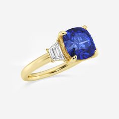 a yellow gold ring with a blue sapphire and two white diamonds on the side, set in