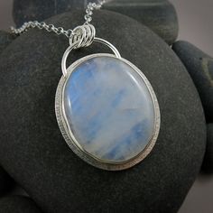 Expertly crafted and one of a kind, the Large Rainbow Moonstone Halo Necklace is a stunning piece of jewellery. This handcrafted sterling silver necklace features a large oval rainbow moonstone with an iridescent blue glow. A textured silver "halo" surrounds the stone, adding a unique touch to this statement necklace. Chain is 18" in length.  If you would prefer a 16" or 20" chain please leave a note in the box at checkout. Product Details: *This necklace is ready to ship.  Will ship within 3 bu Circle Jewelry, Blue Glow, Halo Necklace, Fossil Jewelry, Jewelry Knots, Iridescent Blue, June Birthstone Jewelry, Gold Jewelry Earrings, Halo Pendant