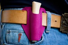 a pink leather belt with a wooden holder in the back pocket on someone's jeans