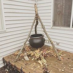 a pot sitting on top of a wooden deck next to a tree branch and broom