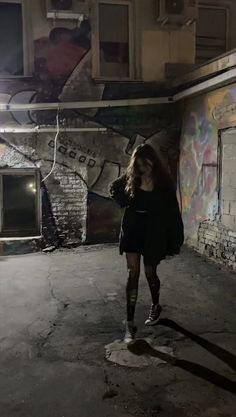 a woman is walking in an empty room with graffiti on the walls and flooring