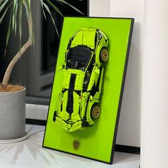 a green car is on display in front of a potted plant and a window