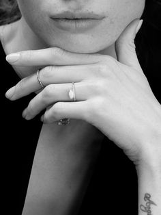 a close up of a person with a ring on her finger and a cross tattoo