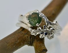 Oak and Acorn Ring Original Design  Made in the USA This bud branch engagement ring features a most beautiful 6 mm moss agate stone. The coordinating band features a very elegant oak leaf with granulated details in the acorn.  The acorn and leaf are set between a very nicely engraved branch band.  This is a great ring and perfect for the nature enthusiast. I can make this ring with different stones or in 14, or 10 karat white, yellow, or rose gold. Rings in photos are sterling silver. I can also make with a patina finish just let me know in notes to seller.  I can also make these rings in 10 or 14 karat white, yellow, or rose gold. If you prefer a different stone please email me. Nature-inspired Rings With Natural Inclusions For Promise, Nature-inspired Promise Rings With Natural Inclusions, Acorn Ring, Butterfly Engagement Ring, Ring Moss Agate, Engagement Ring Nature, Branch Engagement Ring, Twig Engagement Ring, Nature Enthusiast