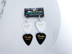 two guitar picks with the words fenderer and paradise on them are hanging from a pair of earrings