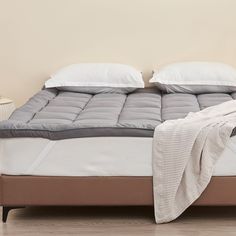 an unmade bed with two pillows on it