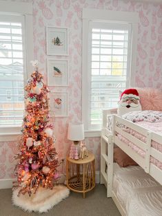 a bedroom decorated in pink and white with a christmas tree next to the bunk bed