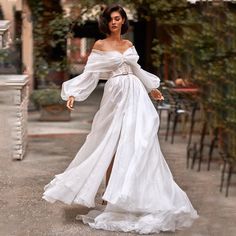 a woman in a white dress is walking down the street with her hand on her hip