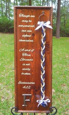 a wooden plaque with white and blue ribbons attached to it in front of some grass