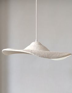 a white object hanging from a string in a room with grey walls and flooring