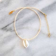 Channel your inner mermaid with this delicate cowrie shell choker. Choose from simple solids or exclusive color mixes for a beach-ready look. glass seed beads genuine cowrie puka shell pendant durable and flexible beading wire gold-plated lobster claw closure, crimps, crimp covers and 2" extension chain lead-free and nickel-free length is approximately 13.5" with a 2" extension chain packaged with a logo kraft card in a clear resealing bag for storage EXCLUSIVE STYLES BLUSH MIX: ivory, cream, bl Beaded Cowrie Shell Beachy Jewelry, Beachy Beaded Cowrie Shell Jewelry, Beachy Cowrie Shell Beaded Jewelry, Beaded Cowrie Shell Strand Jewelry, Adjustable Minimalist Choker For Beach, Dainty White Shell Necklace, Cowrie Shell Necklace As A Gift, Cowrie Shell Necklace As Gift, Cowrie Shell Necklace Gift