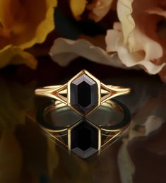 a black diamond ring sitting on top of a table next to some flowers and petals