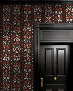 a black door in front of a floral wallpaper