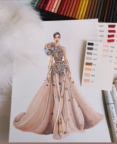 a drawing of a woman's dress on top of a table next to colored pencils