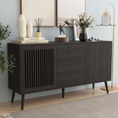 a wooden sideboard with two vases on top of it next to a plant