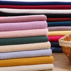 a basket full of folded towels sitting on top of a wooden table next to blankets