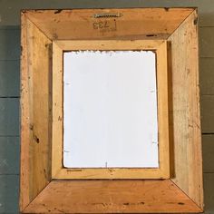 a wooden frame hanging on the wall with a white board in it's center