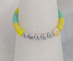 This smile bracelet is the perfect colors of the beach sea foam green and the color of the sand in your toes.     It also reminds you to smile which we all need sometimes. Fun Yellow Beaded Bracelets For Beach, Fun Yellow Beaded Bracelet For Summer, Green Fun Friendship Bracelets With Colorful Beads, Fun Green Friendship Bracelets With Colorful Beads, Fun Green Stretch Bracelet For Friendship, Fun Green Stretch Bracelet With Letter Beads, Fun Green Friendship Bracelet With Colorful Beads, Green Stretch Bracelet With Letter Beads In Fun Style, Casual Yellow Beaded Bracelets With Smiley Face