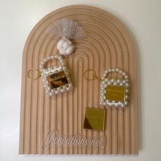 two key chains are attached to a wooden plaque with pearls and beads on it, along with a bow